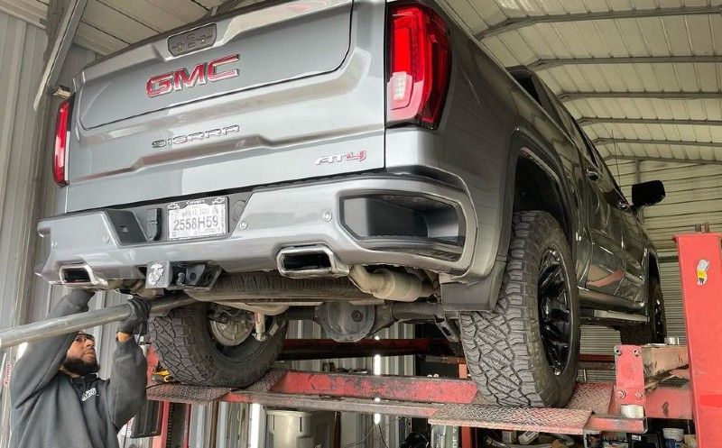 A gmc truck is sitting on a lift in a garage.