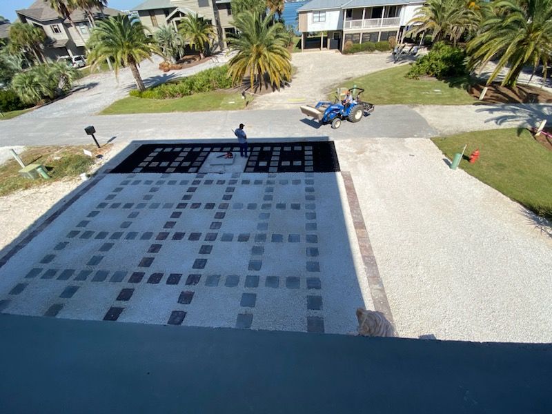Driveway with intricate paving design and a person. A tractor is in the distance.