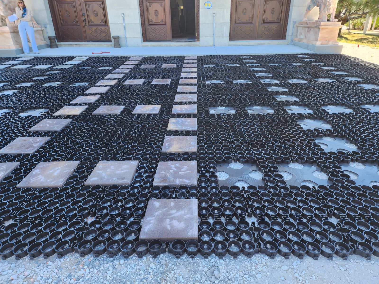 Black grid paving with stepping stones leading to a building entrance.