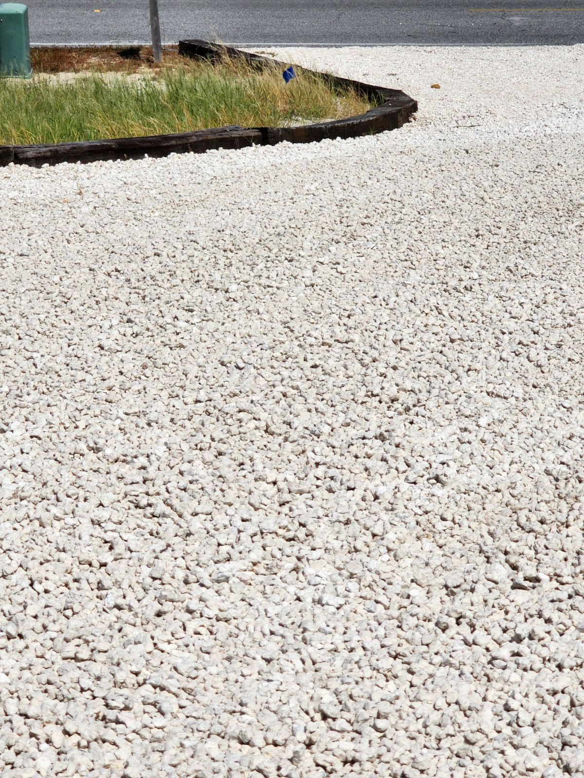 White gravel pathway curves along a small patch of grass bordered by a dark trim.