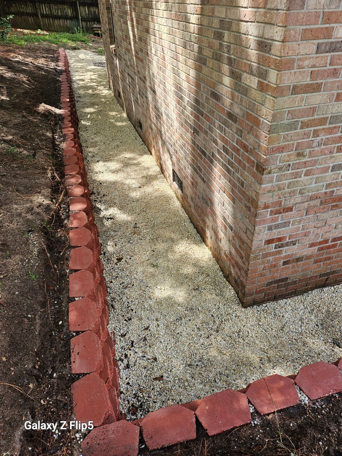 Brick-lined gravel bed next to a brick building corner.
