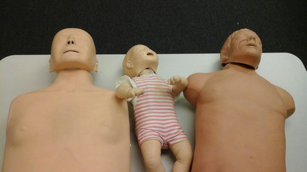 Three mannequins are laying on a table with a baby in the middle