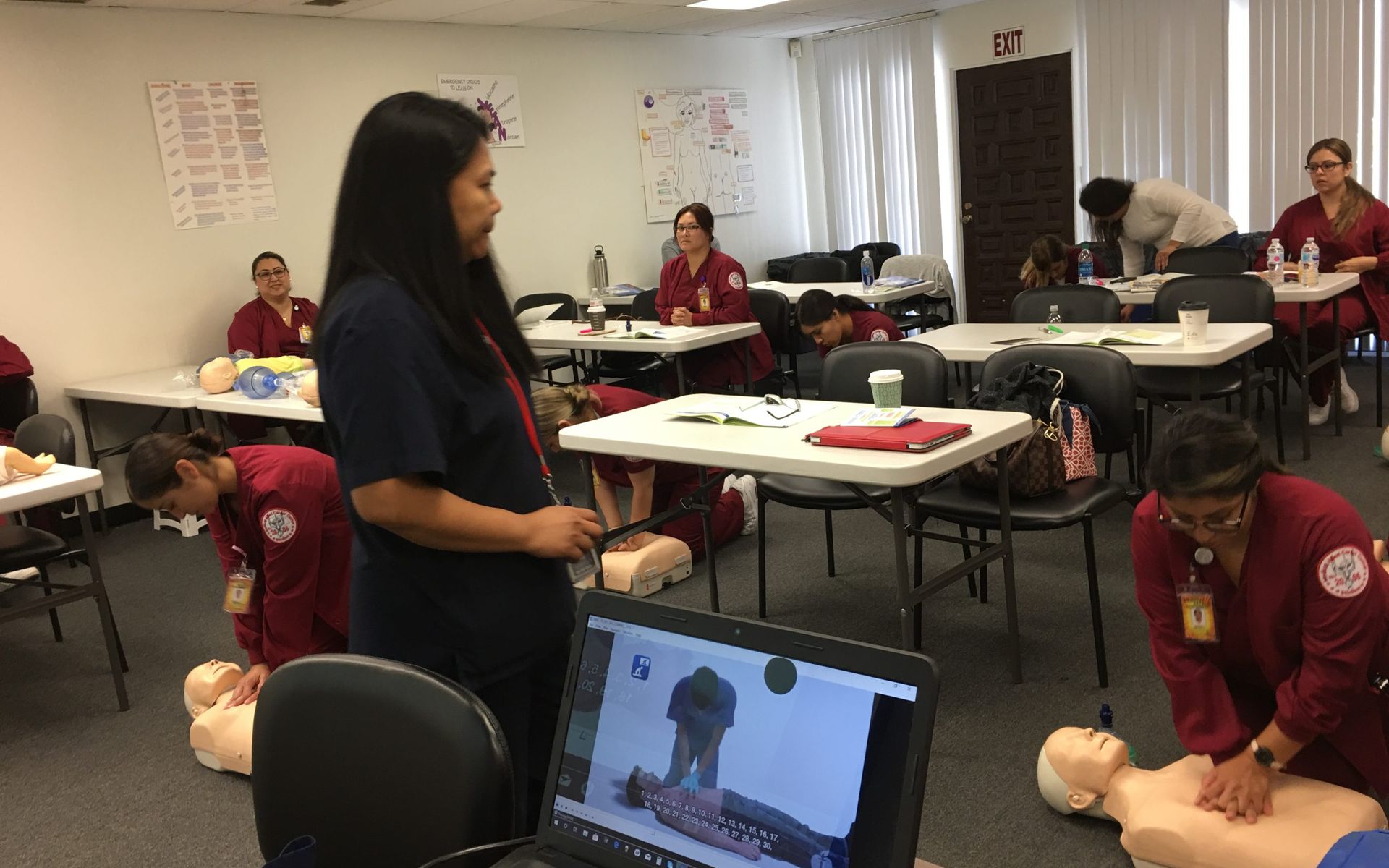 A woman is teaching a group of people how to do a cpr on a mannequin.