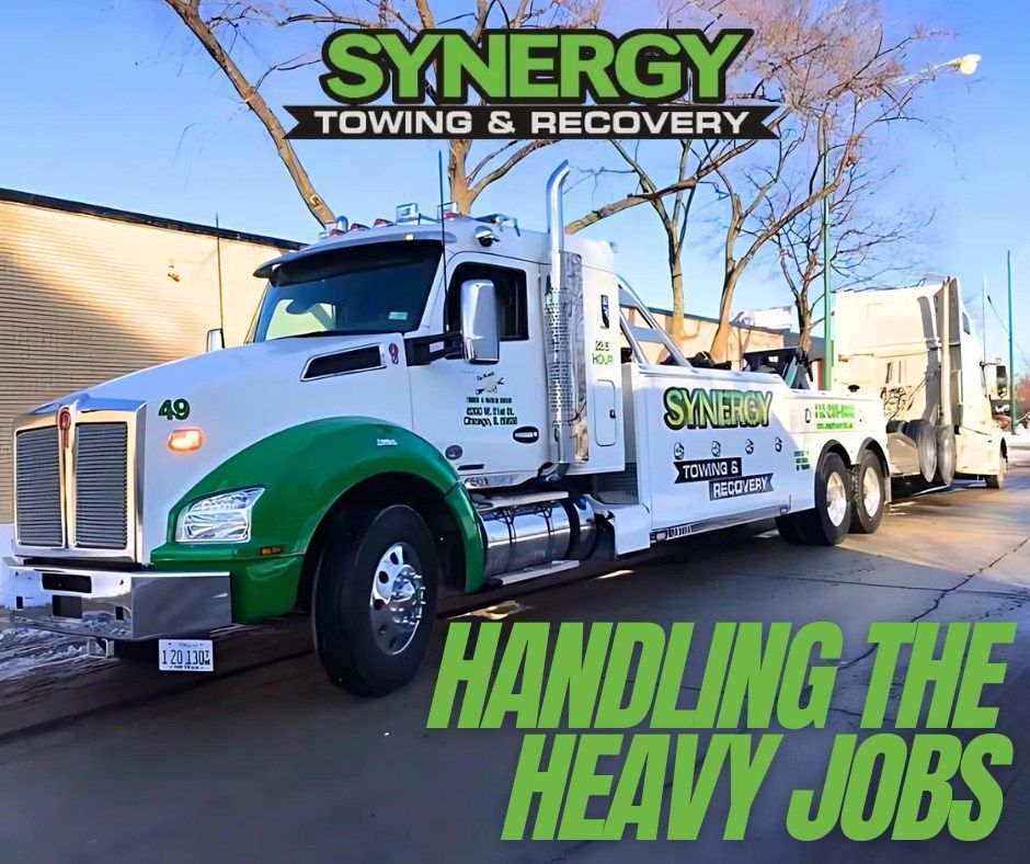 White and green Synergy Towing truck towing a white semi-truck; 