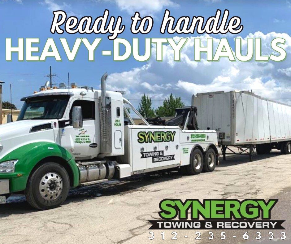 White and green tow truck with trailer, text says 