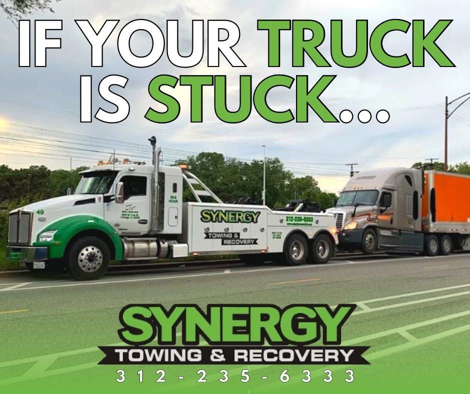 Tow truck pulling semi-truck; green and white, roadside setting, text: 