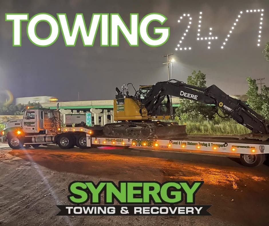 Towing truck transporting excavator at night. 