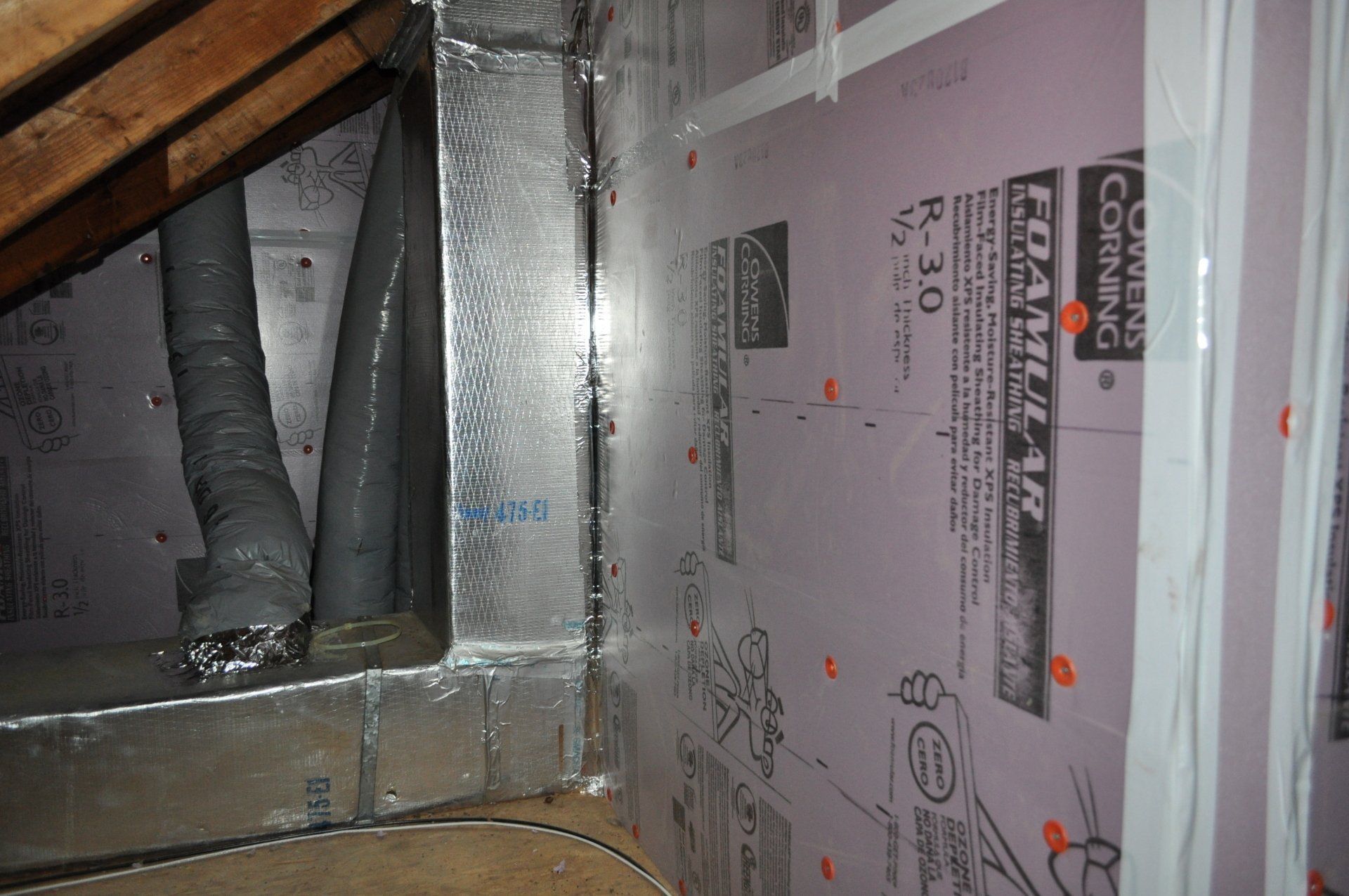 Insulated HVAC ductwork and foil-faced paneling inside an attic or crawlspace.