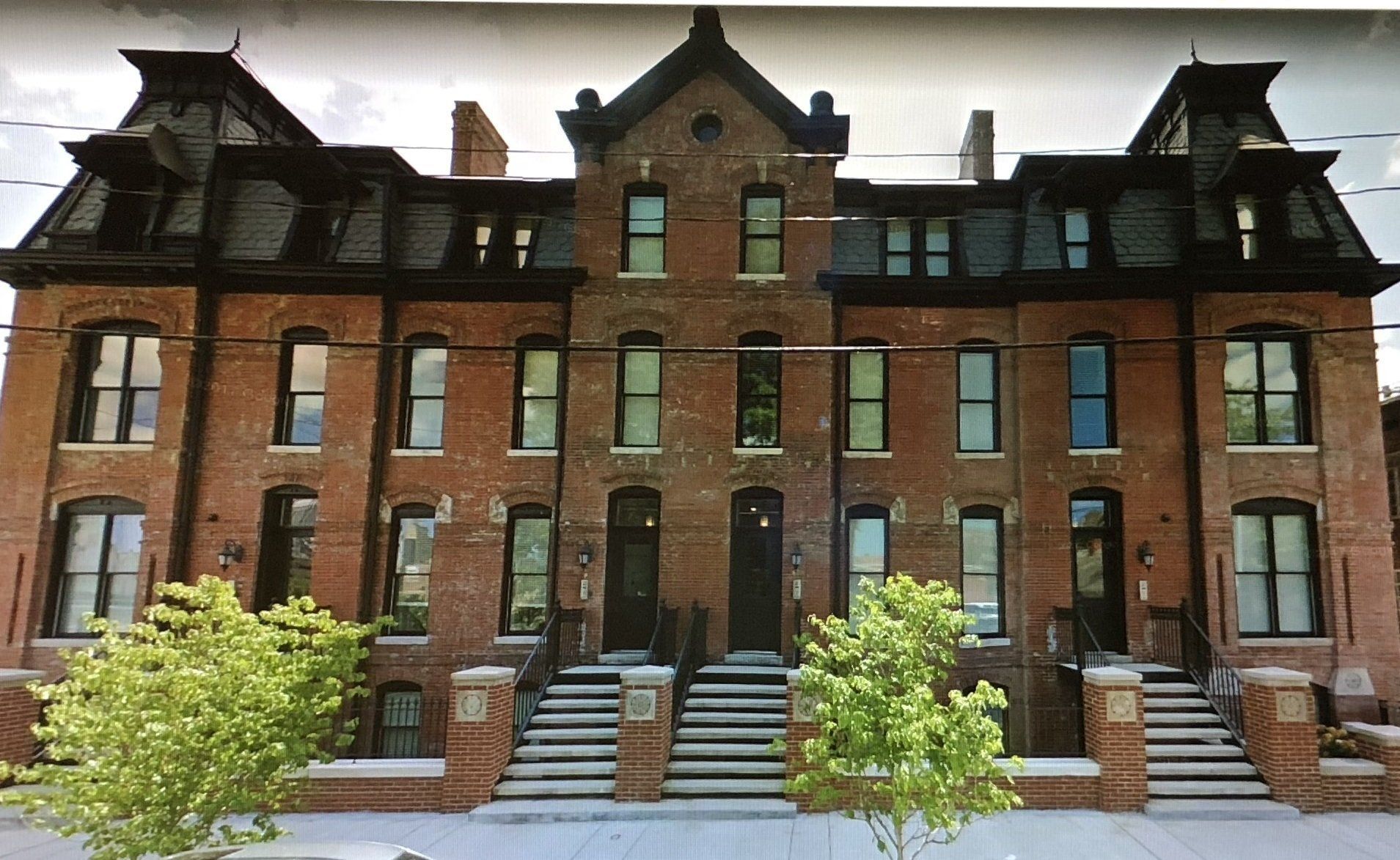 Row of historic red-brick townhouses with steep dark roofs and front steps