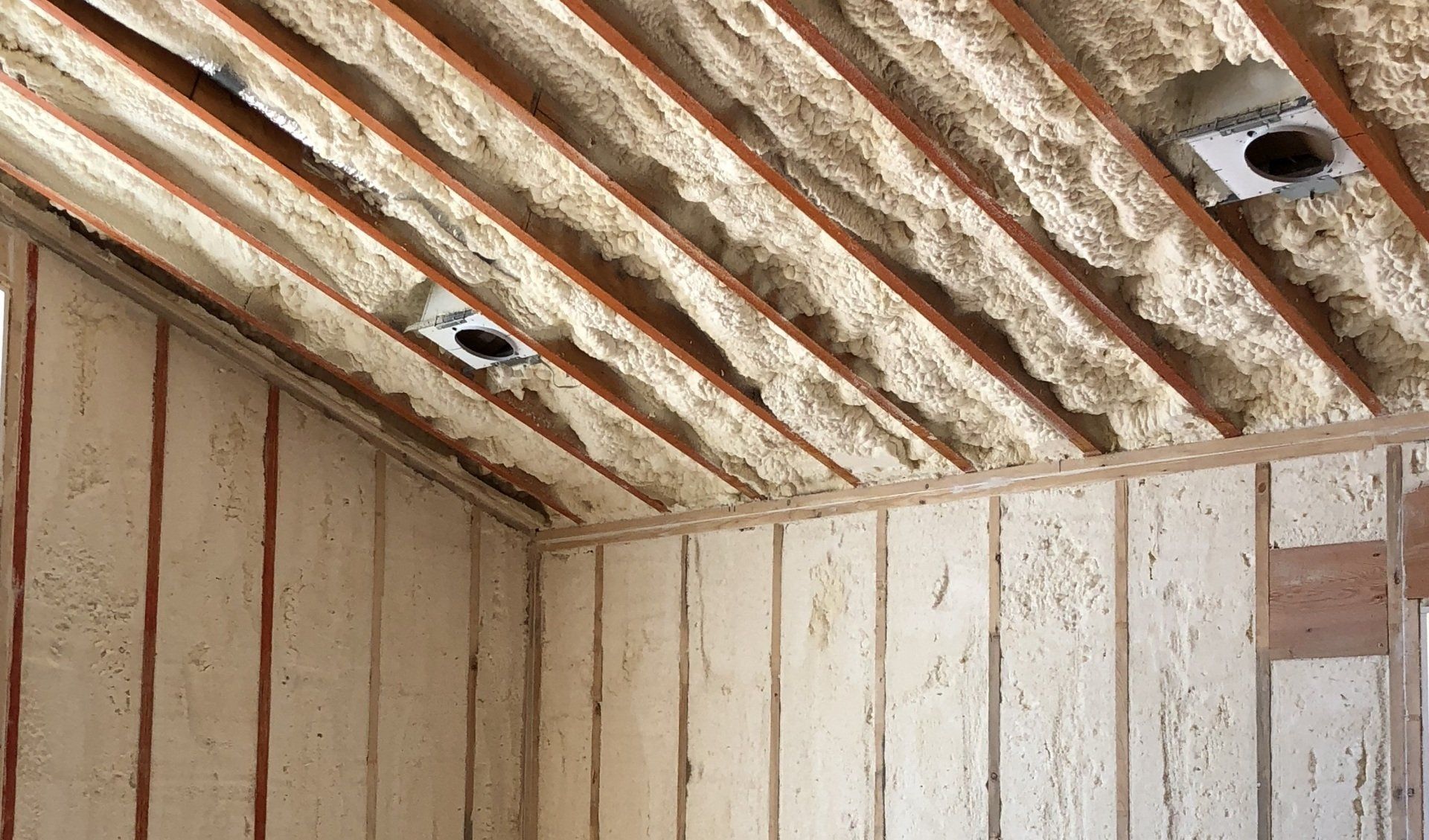 Interior of a rustic wooden room with exposed beams and a small wall opening near the ceiling