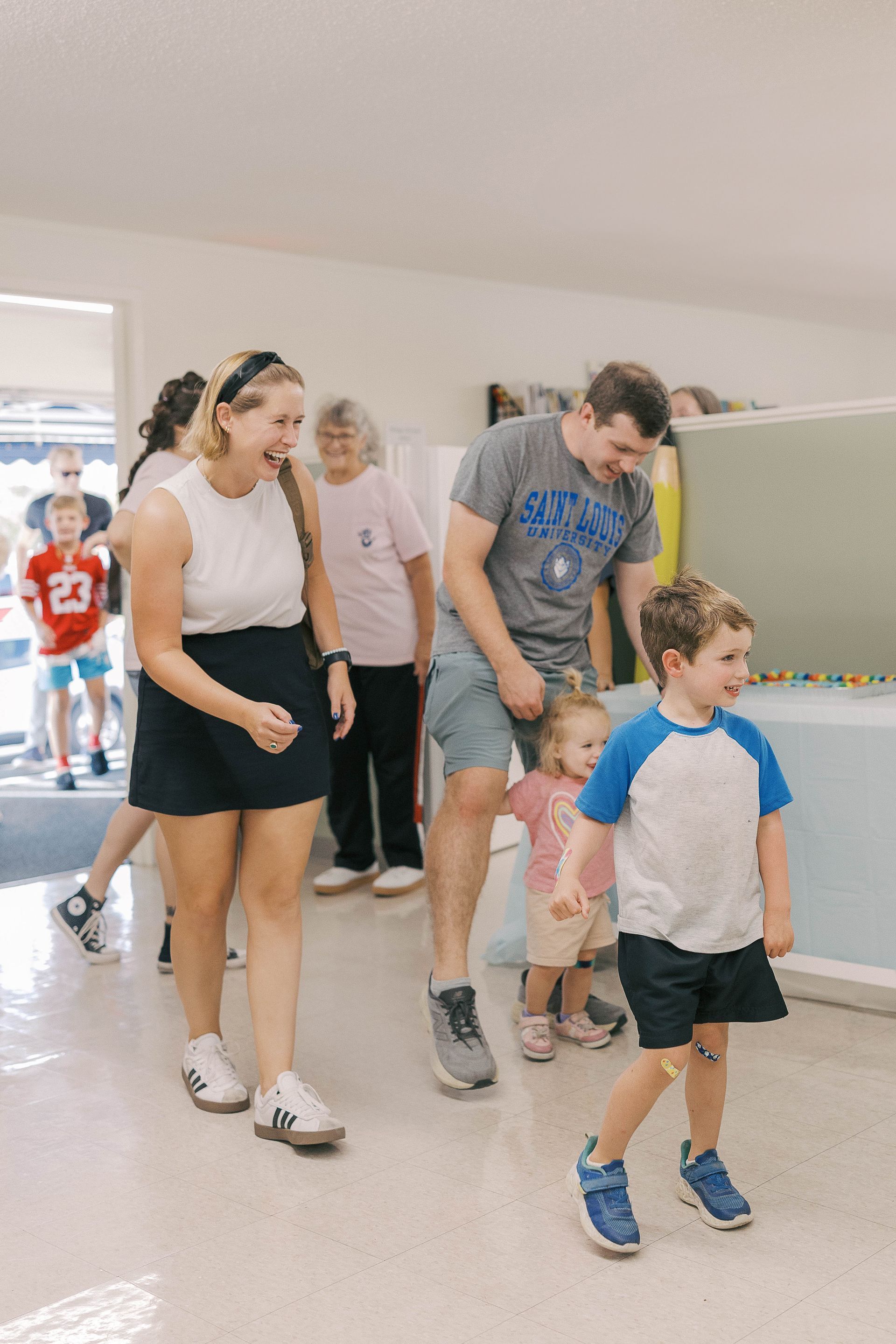A group of people, including children, walking in a brightly lit room.