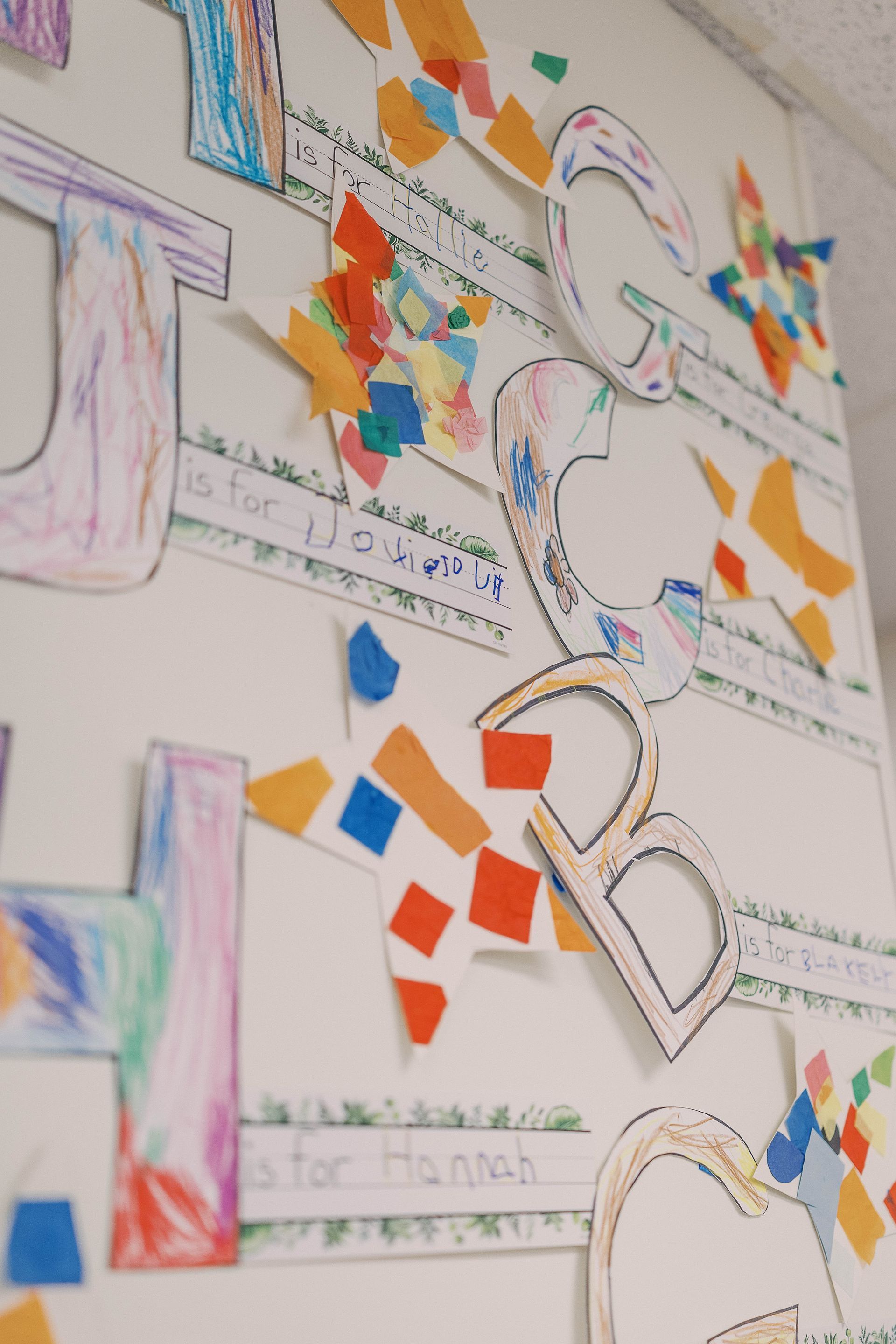 Colorful alphabet art on a wall with torn paper accents, possibly in a classroom.