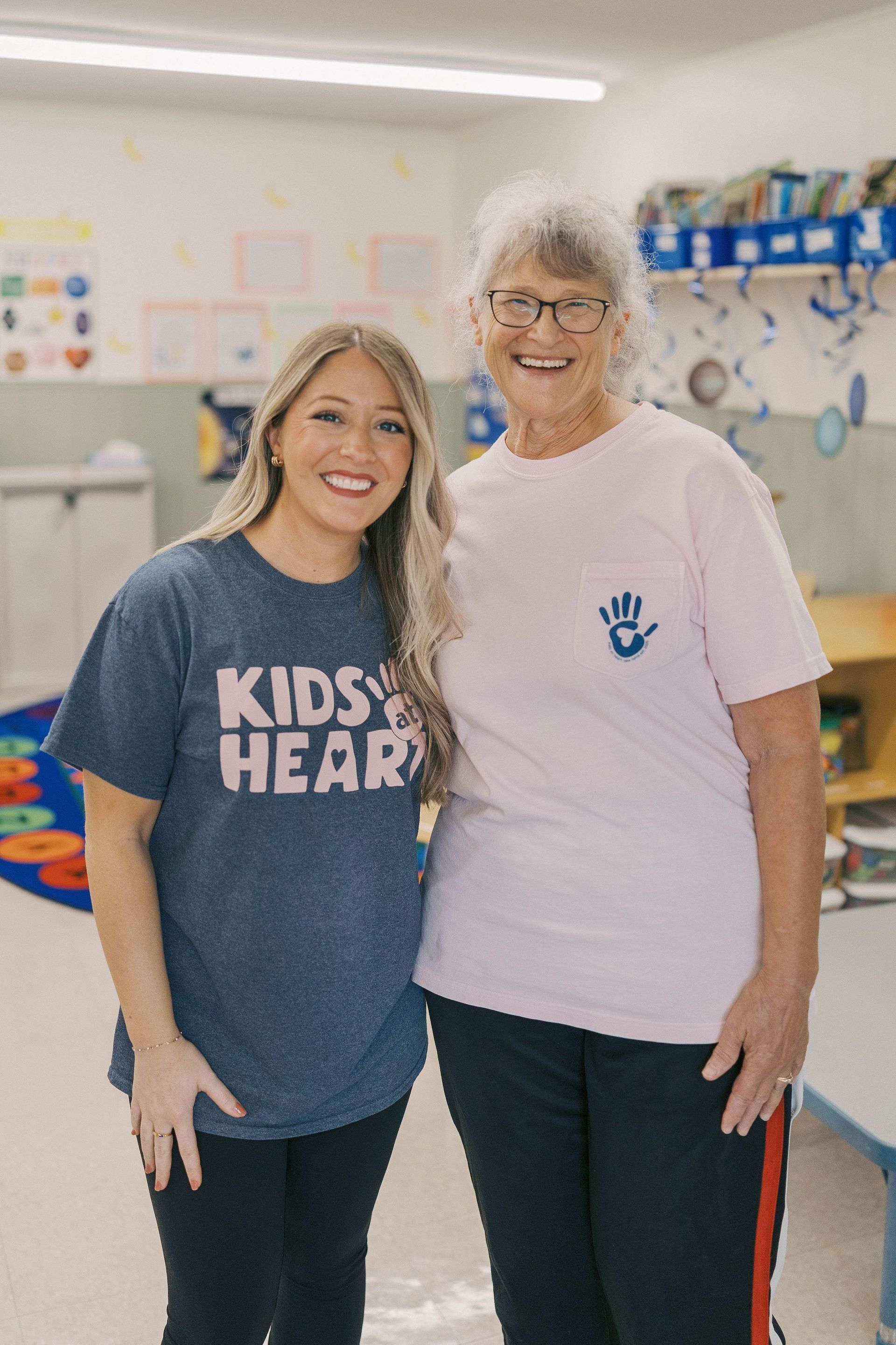 Two women smiling in a brightly lit classroom.