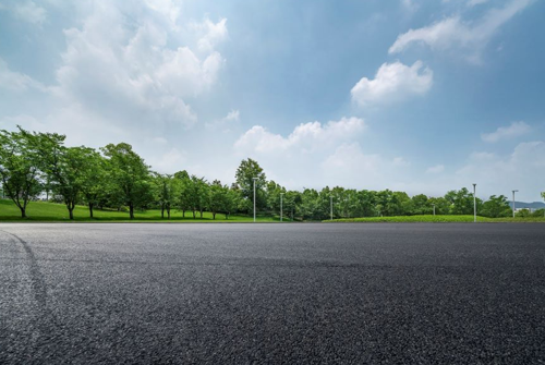 An empty road with trees on the side and a blue sky in the background