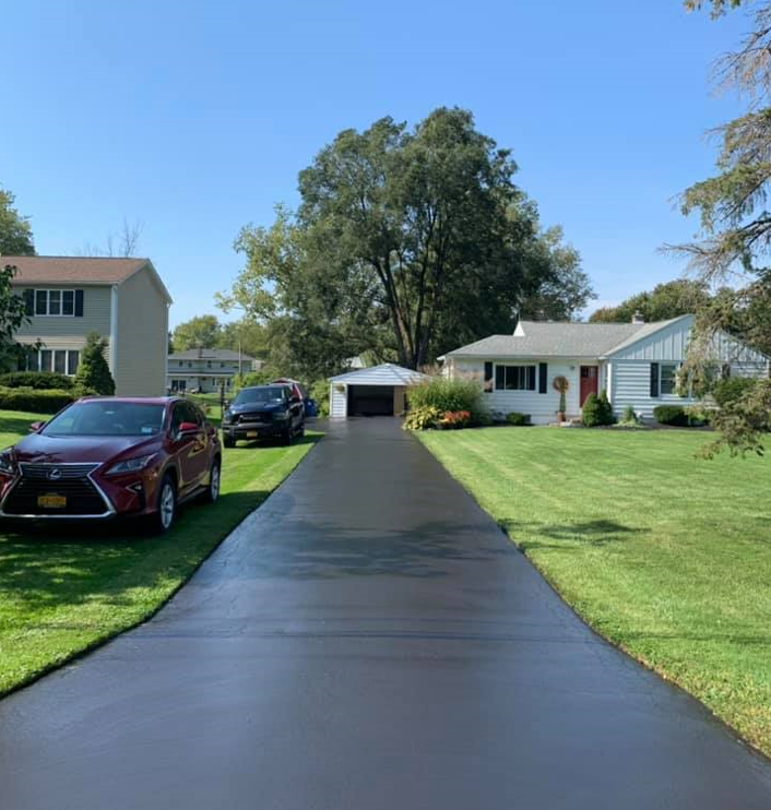 A red car is parked on the side of a driveway next to a house.