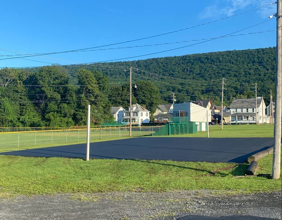 A baseball field with a fence and houses in the background.