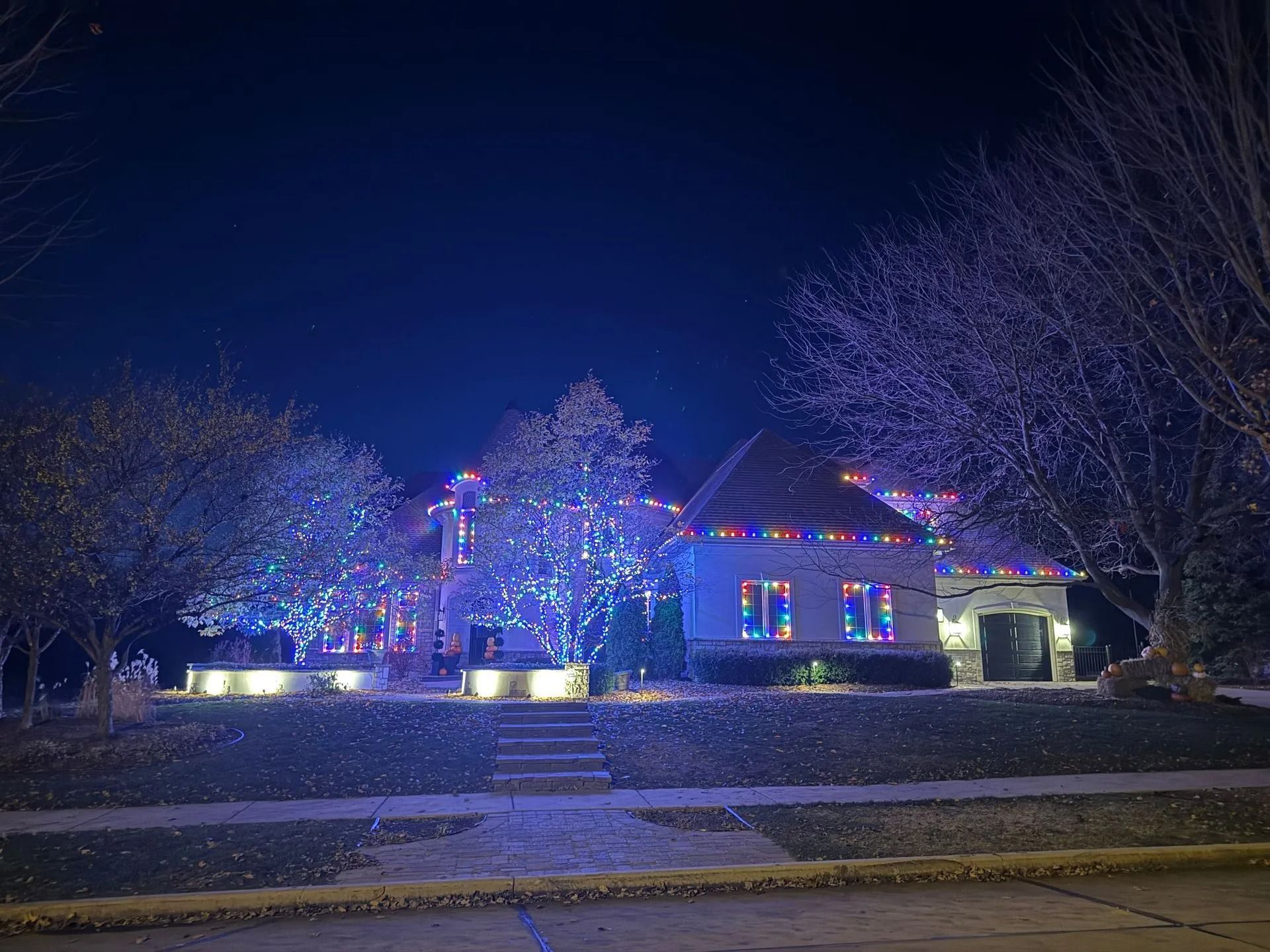 House decorated with blue and multicolored Christmas lights at night.