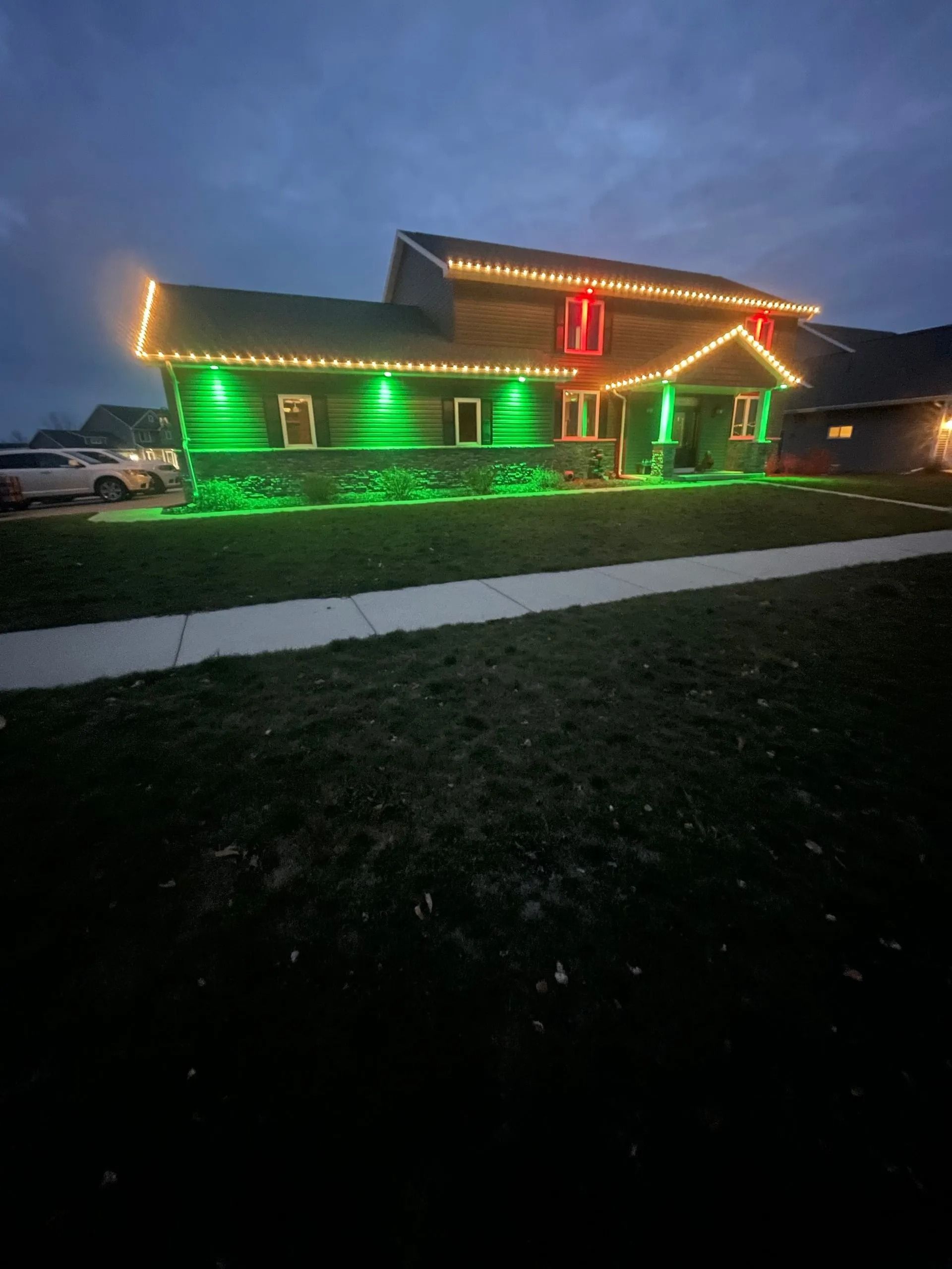 House decorated with green and red Christmas lights, illuminating the exterior.