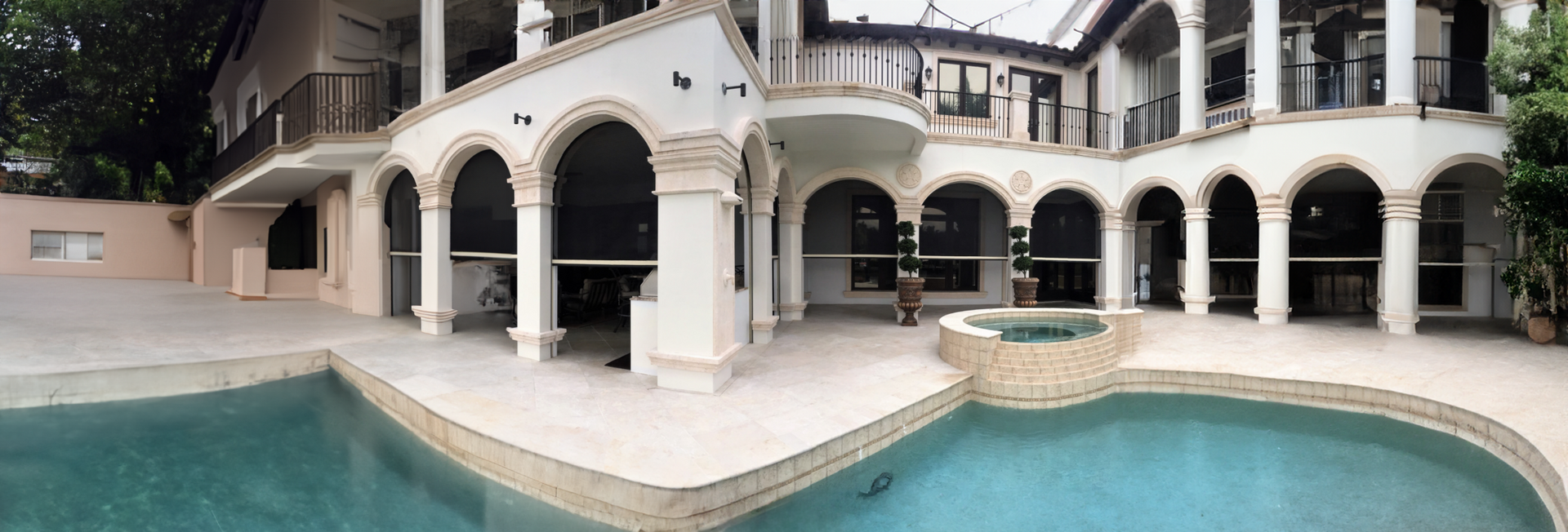Luxury villa courtyard with arched balconies and a turquoise swimming pool