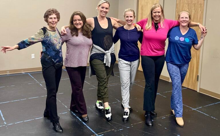 A group of women are posing for a picture in a dance studio.
