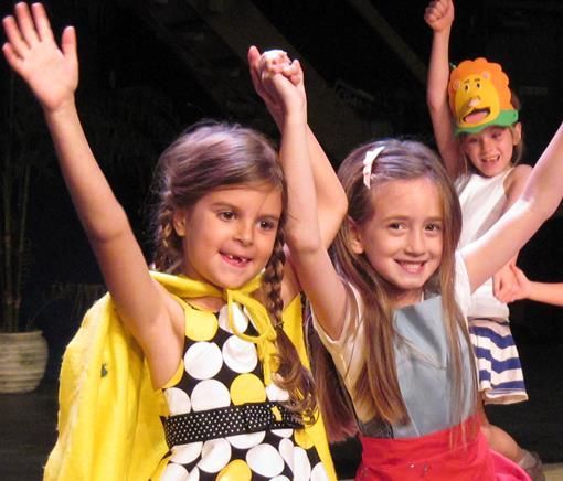 A group of young girls are raising their arms in the air