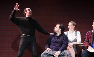 A man is standing in front of a group of people on a stage.