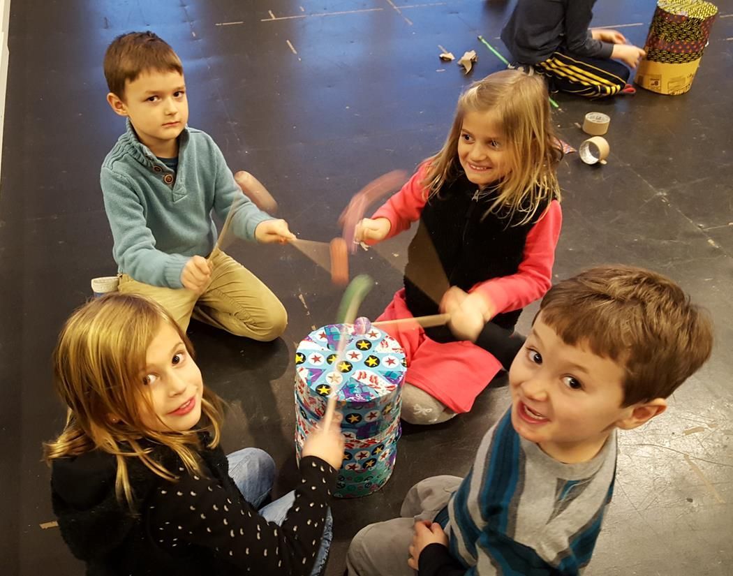 A group of children are sitting on the floor playing instruments