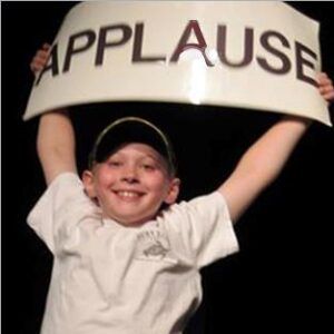 A young boy is holding up a sign that says applause