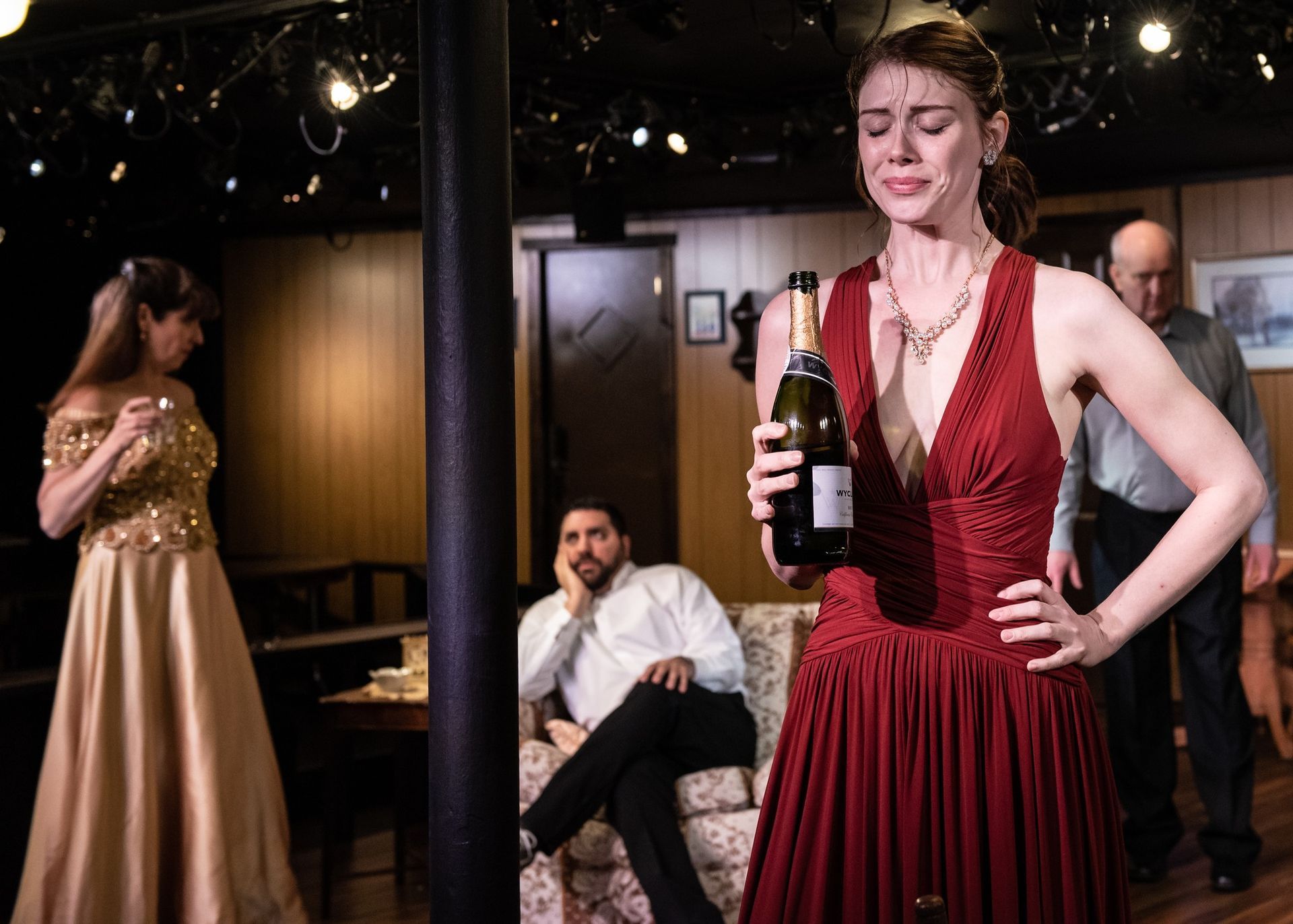 A woman in a red dress is holding a bottle of wine.