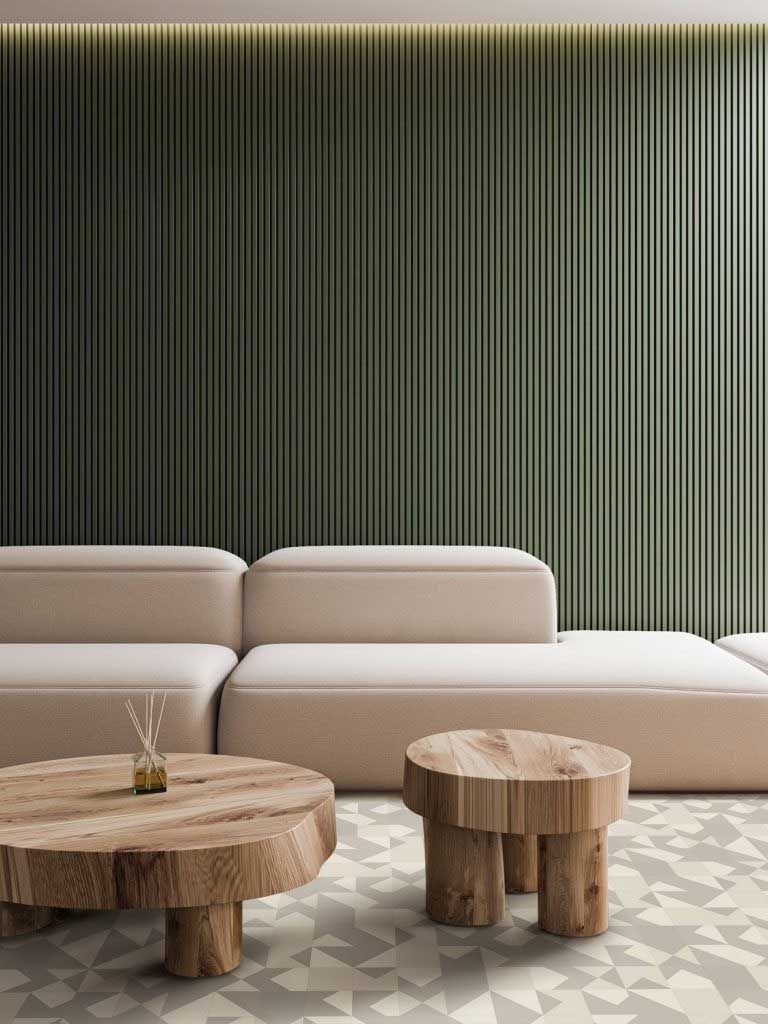 Beige sectional sofa and wooden tables in a room with patterned floor and olive green vertical panel wall.
