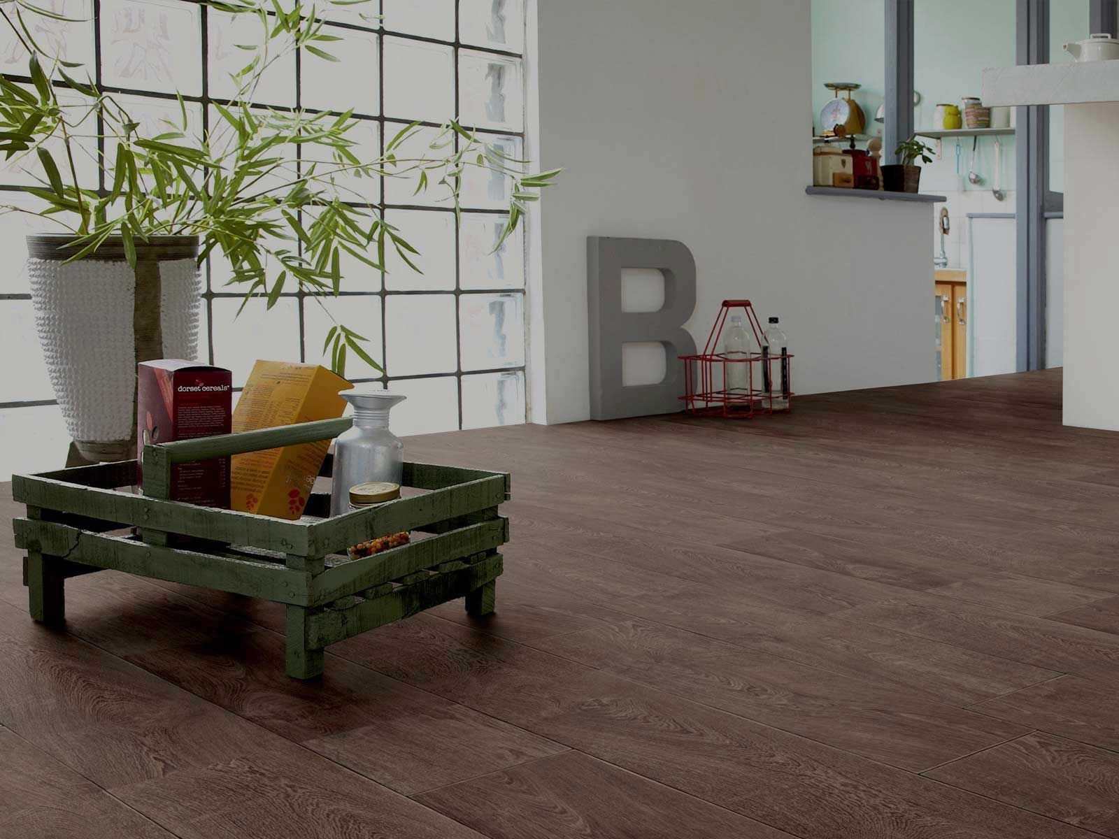 Wooden flooring with a green wooden crate containing items, near a window and a large gray 