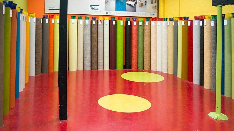 Colorful rolls of material line the walls of a room with a red floor and two yellow circles.
