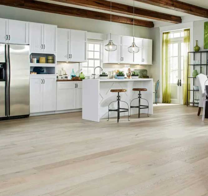 Bright, white kitchen with island, stainless steel appliances, and light wood flooring.