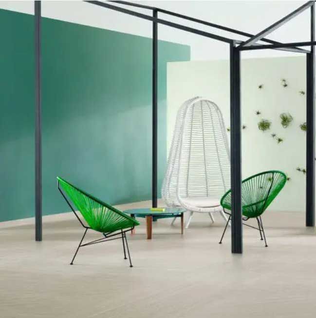Green chairs and white chair in modern room with green and white walls and a black frame structure.