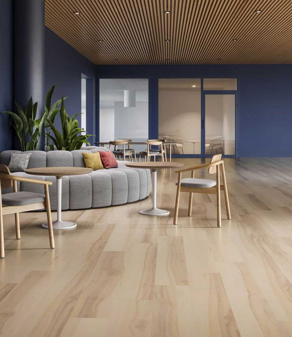 Modern lounge area with blue walls, wood ceiling, round sofa, tables, chairs, and plants.