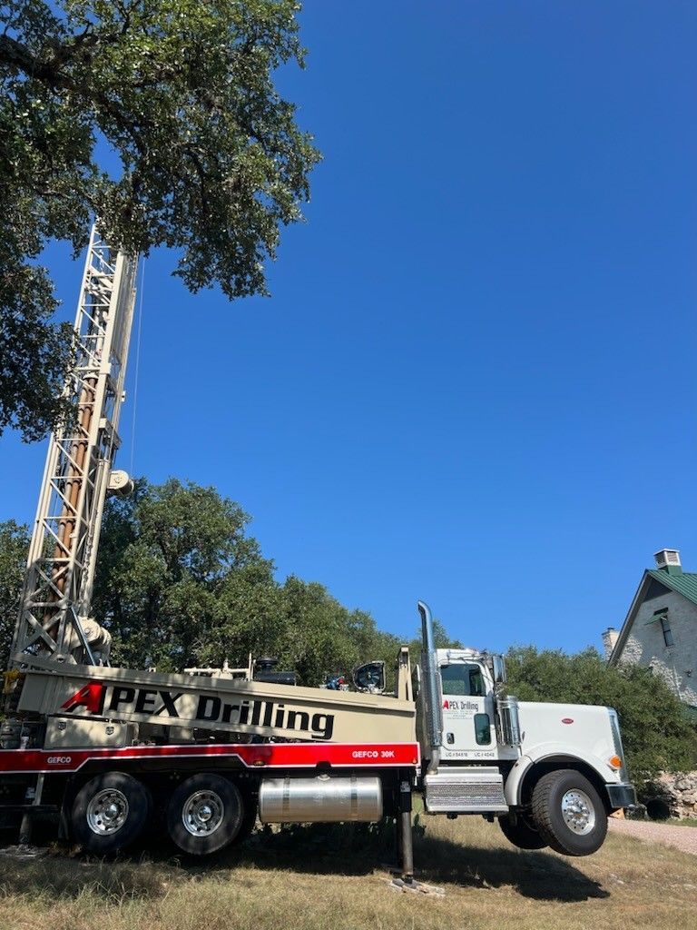 An apex drilling truck is parked in front of a house