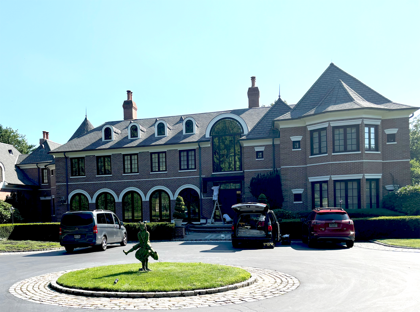 A large brick house with cars parked in front of it