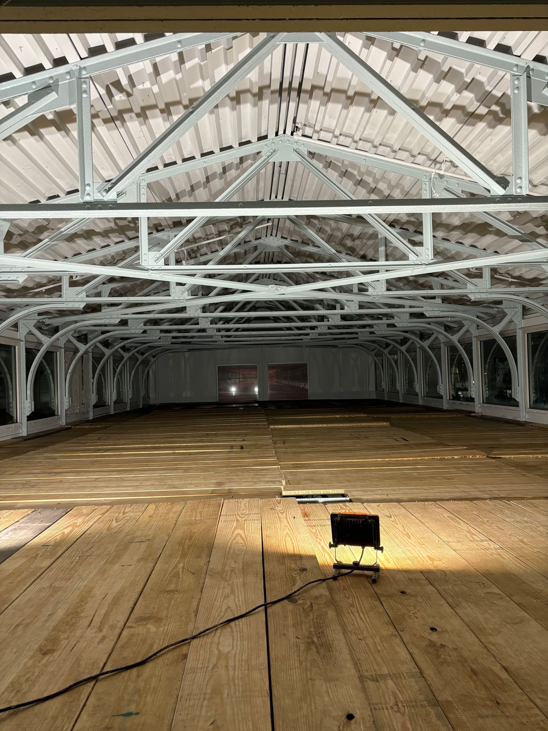 A large empty warehouse with a wooden floor and a light on the floor.