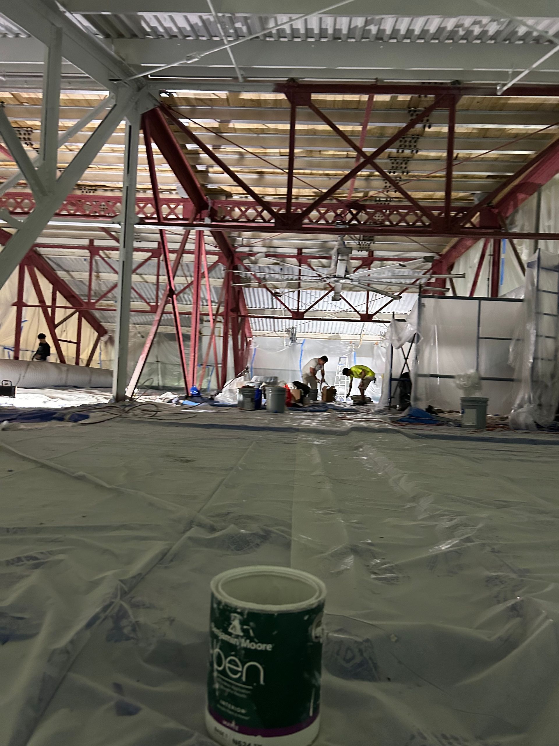 A can of paint is sitting on the floor of a building under construction.