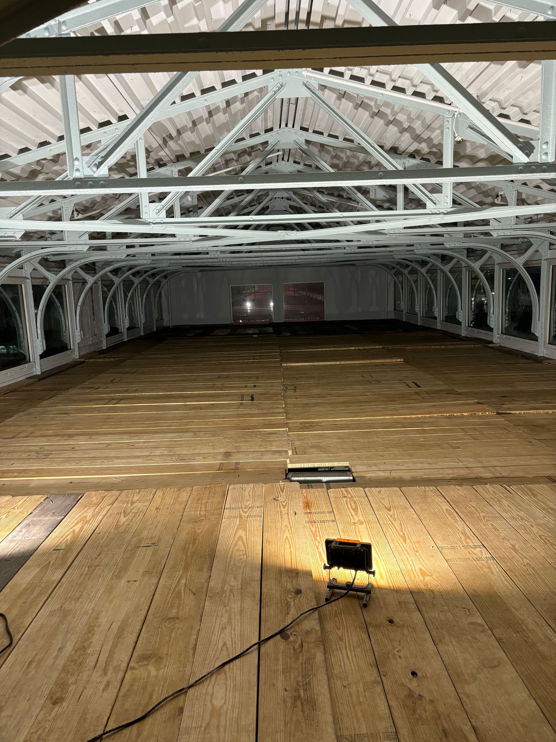 A large empty room with a wooden floor and a light on the floor.