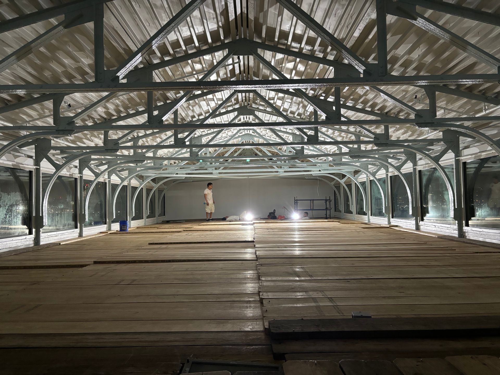 A large empty warehouse with a wooden floor and a light on the floor.