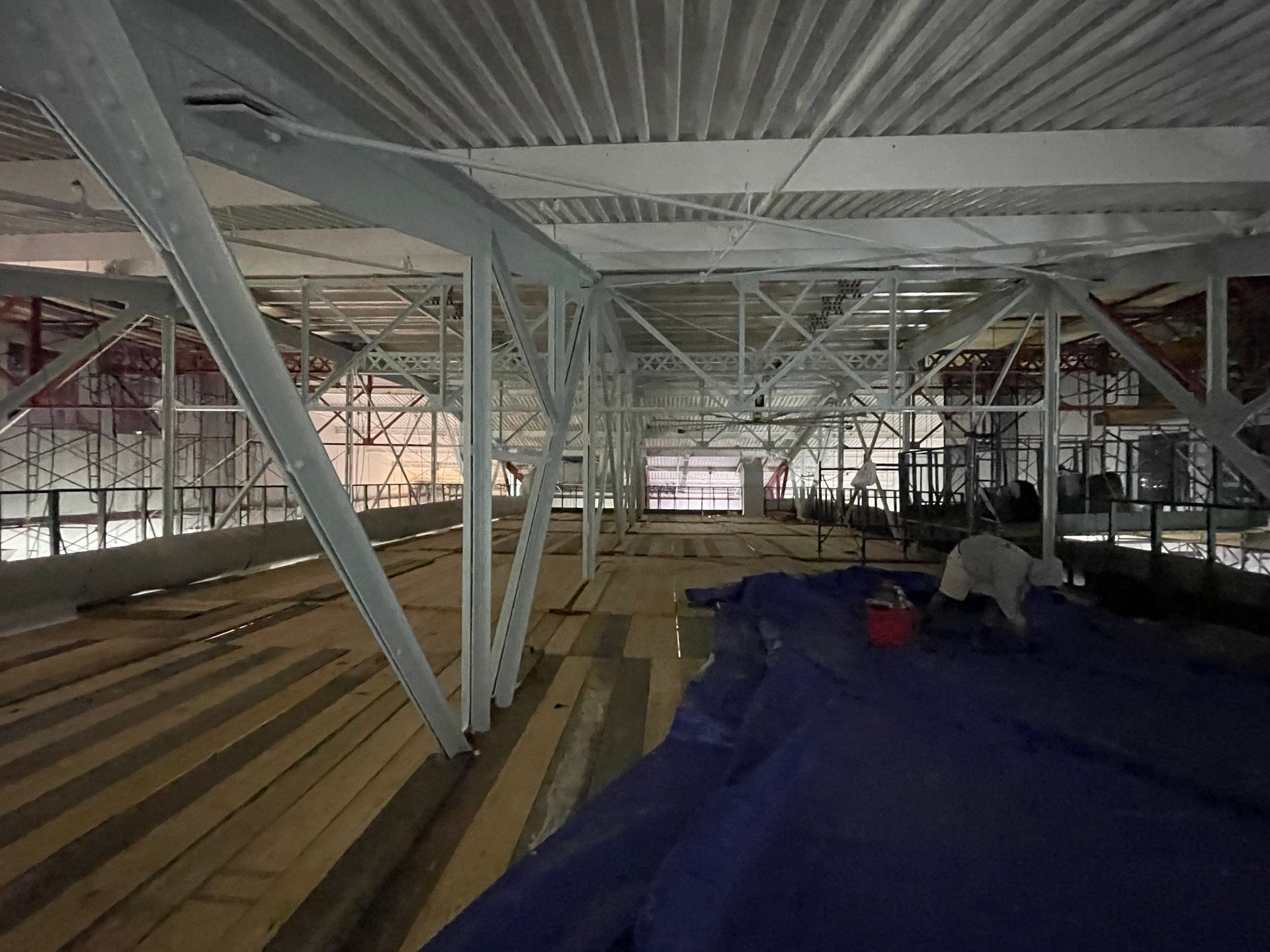 A large building under construction with a blue tarp on the floor.