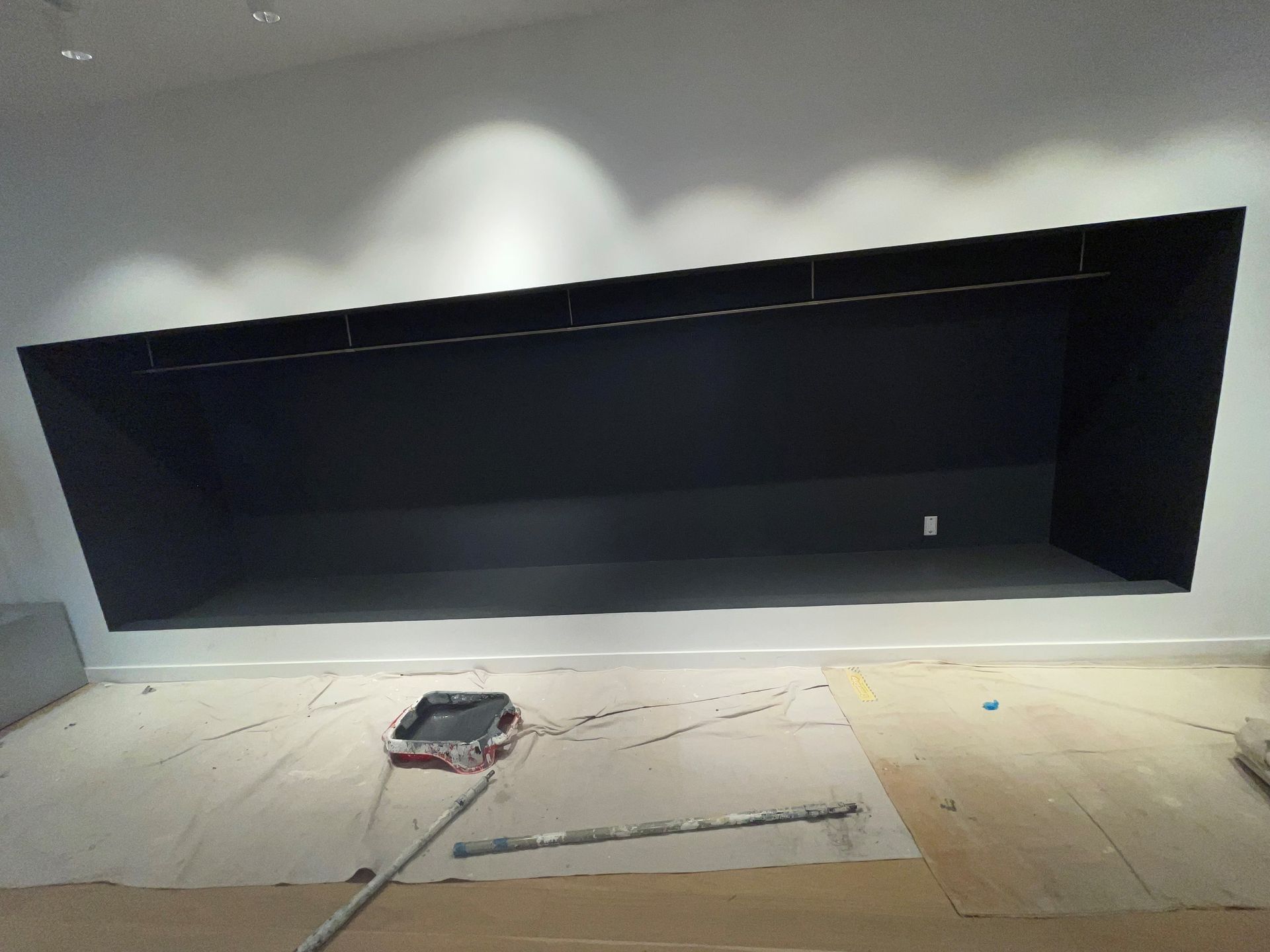 A painting roller is sitting on the floor in front of a wall