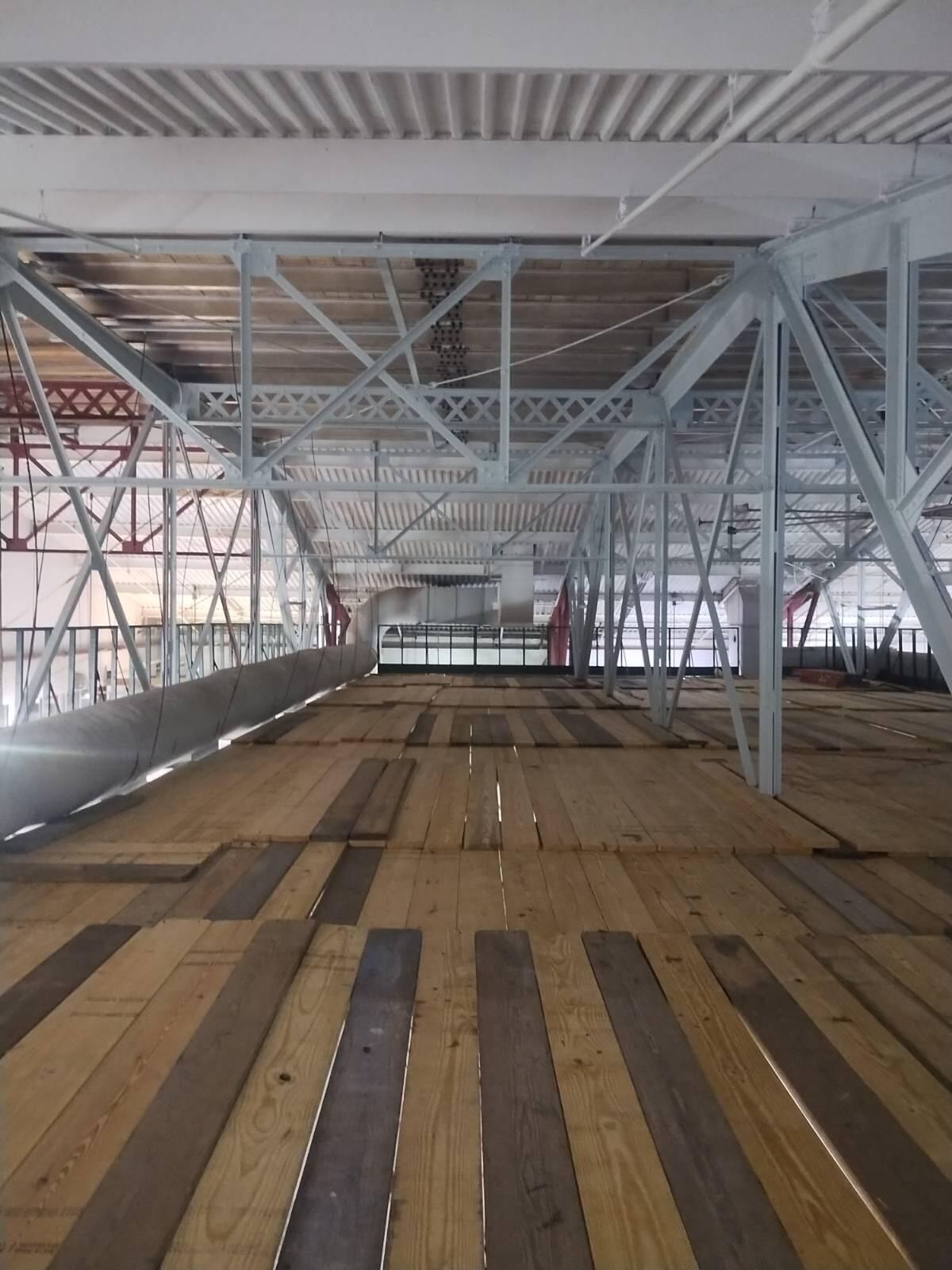 An empty building with a wooden floor and metal beams
