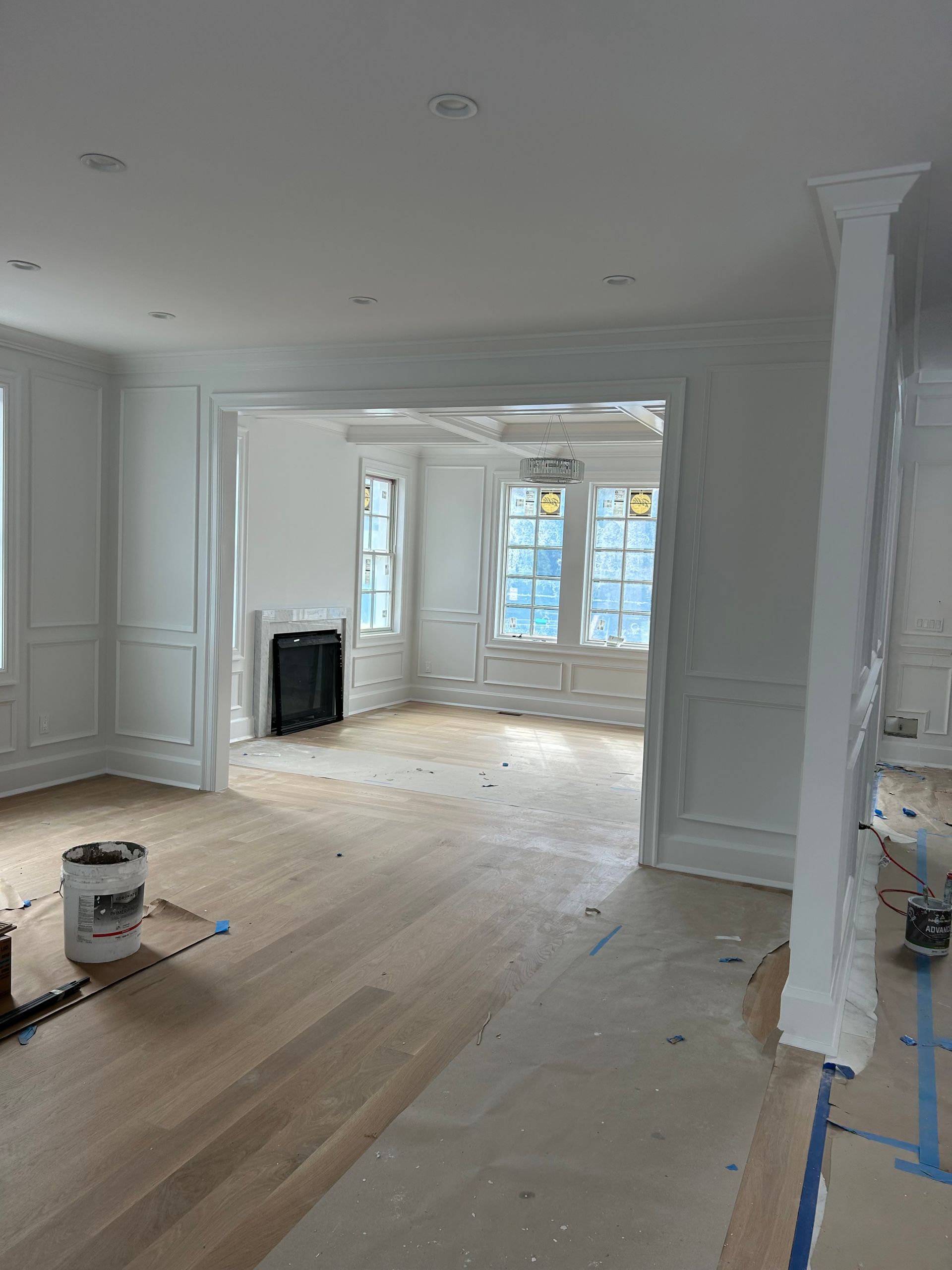 A living room with hardwood floors and white walls is being painted
