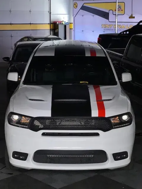 White Dodge SUV with black and red racing stripes parked indoors.