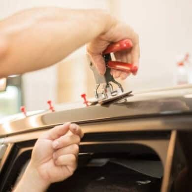 Person using dent puller tool on car roof.