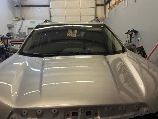 Silver car hood with windshield in a shop.