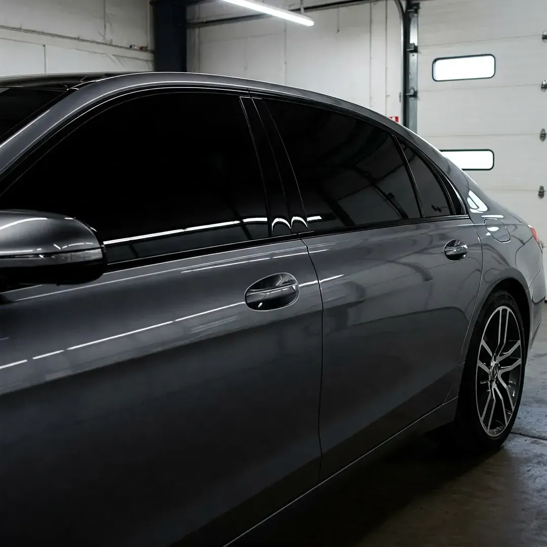 Gray sedan with tinted windows parked inside a garage.