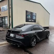 Black Lexus parked outside a building with a banner that reads "Unit 160" and a logo.
